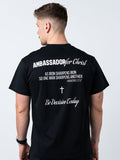 Person wearing a black t-shirt with text and a cross on the back, on a light gray background