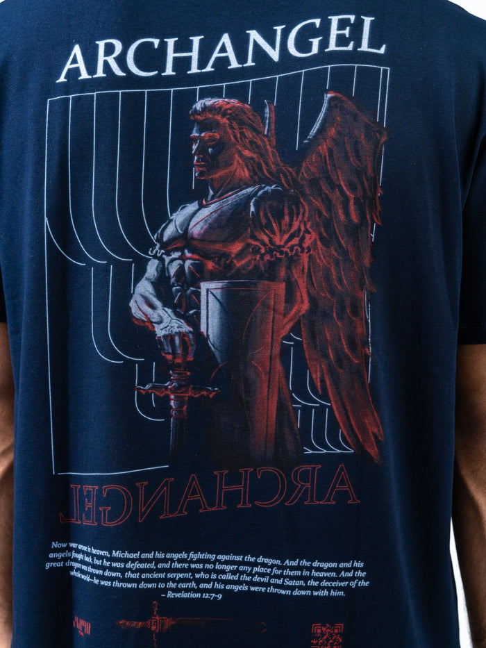 Back view of a navy blue Archangel Michael Premium Oversized Tee featuring a detailed graphic of Archangel Michael with wings and armor, holding a sword and shield, with text referencing spiritual warfare and faith.