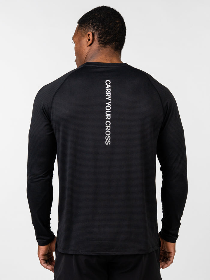 Man wearing a black Carry Your Cross Premium Long Sleeve Tee featuring white vertical text on the back, designed for Christian fitness apparel and faith-based activewear.