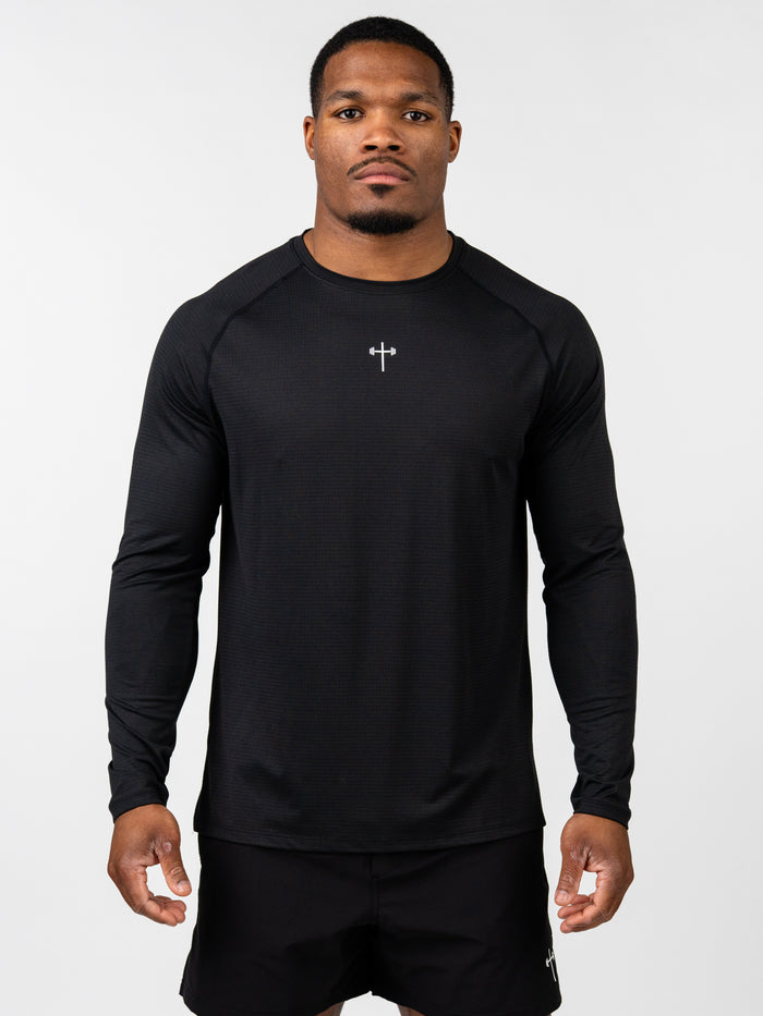 Man wearing a black Carry Your Cross Premium Long Sleeve Tee with a small cross and barbell emblem on the chest, styled for Christian fitness apparel.