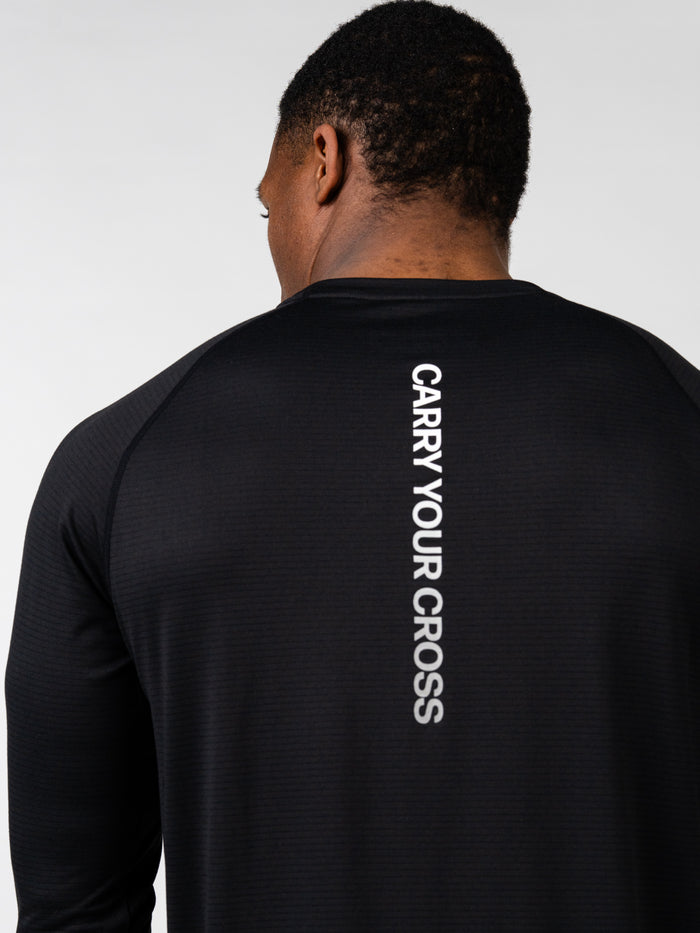 Rear view of a man wearing the Carry Your Cross Premium Long Sleeve Tee in black, featuring vertical white text down the upper back, made for Christian fitness apparel and activewear.
