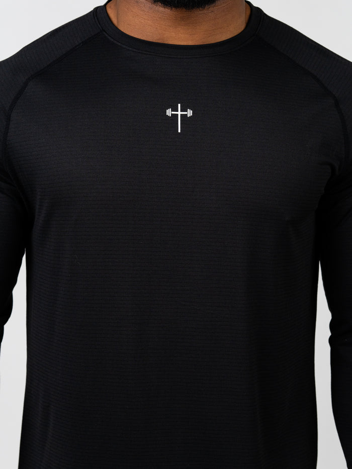 Close-up of a black Carry Your Cross Premium Long Sleeve Tee featuring a small white cross with a barbell design centered on the chest, combining Christian gym clothing and faith-based fitness apparel.