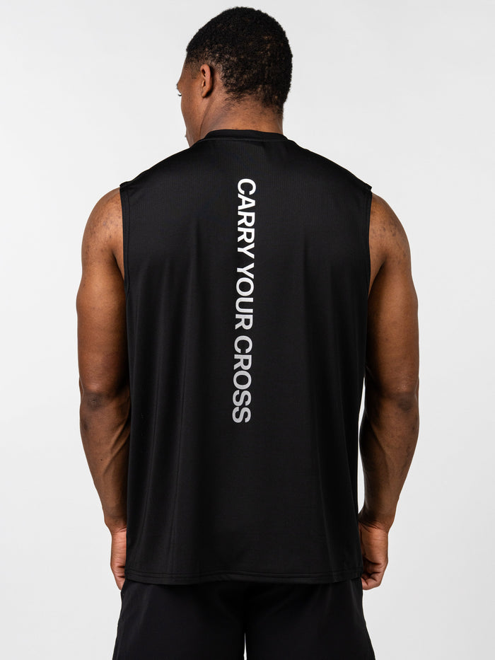 Man wearing the Carry Your Cross Premium Oversized Tank in black, shown from the back, featuring vertical white text "CARRY YOUR CROSS" on a sleeveless athletic shirt.