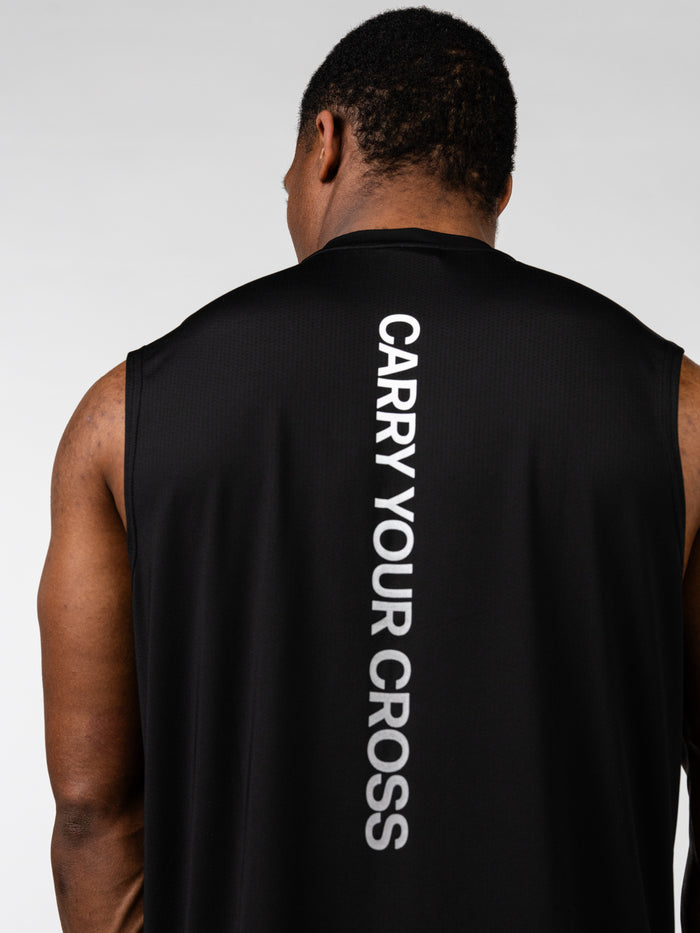 Man wearing a black Carry Your Cross Premium Oversized Tank showing the back with vertical white text, designed for Christian fitness apparel and faith based workout clothes.