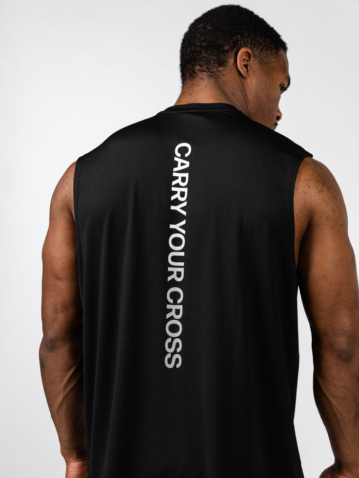 Man wearing black Carry Your Cross Premium Oversized Tank with white vertical text on the back, showcasing Christian fitness apparel for faith-based workouts.