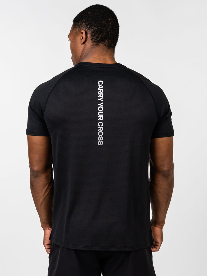 Person wearing a black t-shirt with 'Carry Your Cross' text on the back against a white background