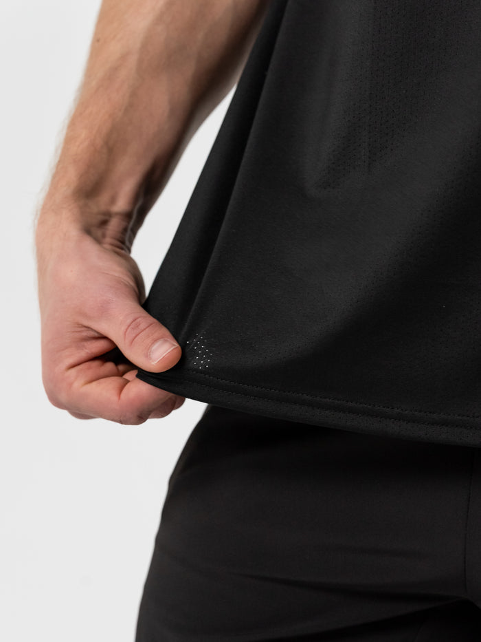 Close-up of a person holding the hem of the black Christian Lifting Club Premium Oversized Tank, showing lightweight, breathable fabric designed for Christian fitness apparel.