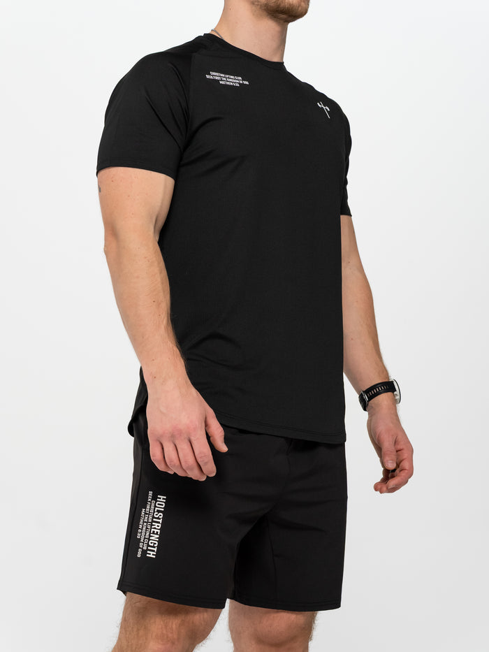 Man wearing black Christian Lifting Club Premium Shorts 7" paired with a black athletic T-shirt featuring minimalist faith-inspired text and logo, styled for workout.