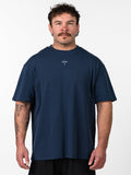 Man wearing a navy blue Classic Oversized Tee with a small white Christian cross and barbell logo on the chest, styled for Christian fitness apparel and activewear.