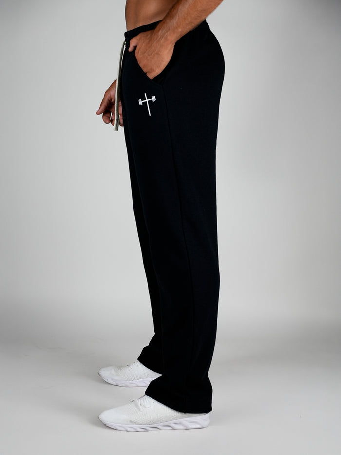 Person wearing black sweatpants with a logo on a gray background