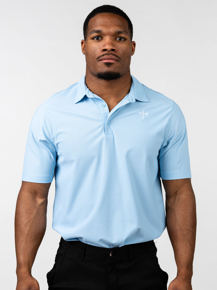 Man wearing a light blue Core Athletic Polo with a subtle Christian cross design on the chest, paired with black pants, showcasing a blend of performance and style.