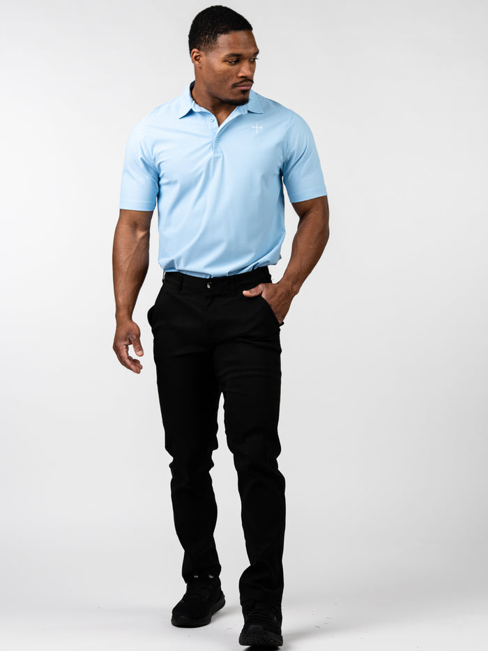 Man wearing a light blue Core Athletic Polo with a subtle cross emblem on the chest, paired with black pants, showcasing comfortable and stylish Christian fitness apparel.