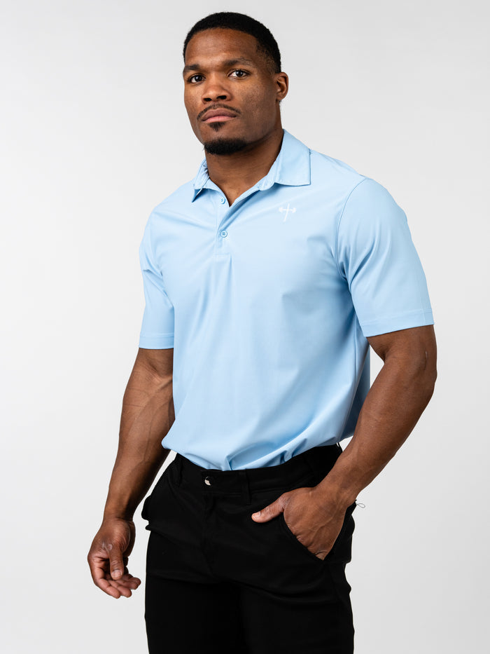 Man wearing a light blue Core Athletic Polo with a subtle Christian cross and barbell logo on the chest, paired with black pants, showcasing a blend of athletic performance and sharp presentation.