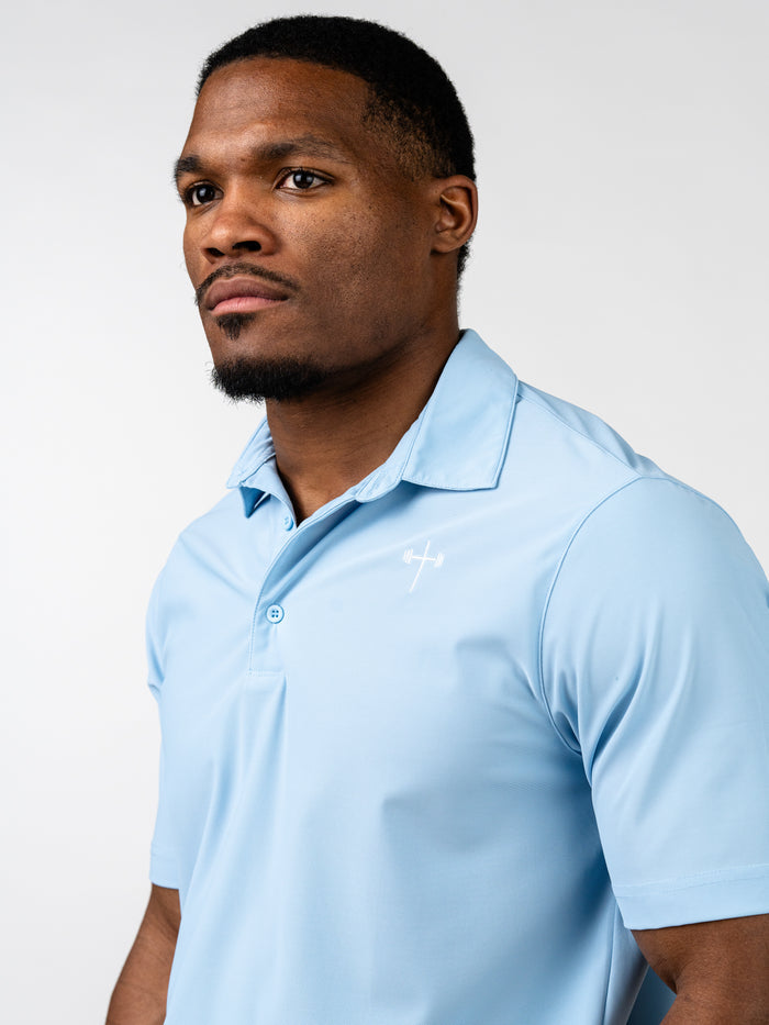 Man wearing a light blue Core Athletic Polo with a subtle cross and barbell design on the chest, showcasing Christian fitness apparel in a clean, professional style.