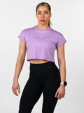 Woman wearing a lavender Cross Essential Crop Tee with a small white cross and barbell graphic, paired with black high-waisted leggings, styled for fitness and activewear.