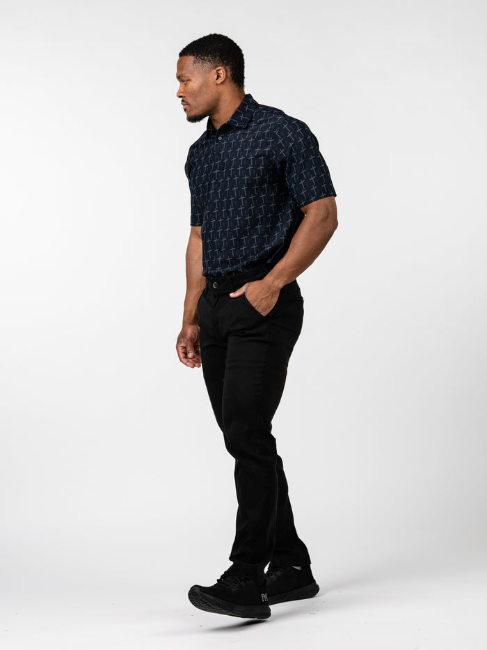 Man wearing Cross Premium Polo with subtle cross pattern, paired with black pants and black athletic shoes, standing against a white background.