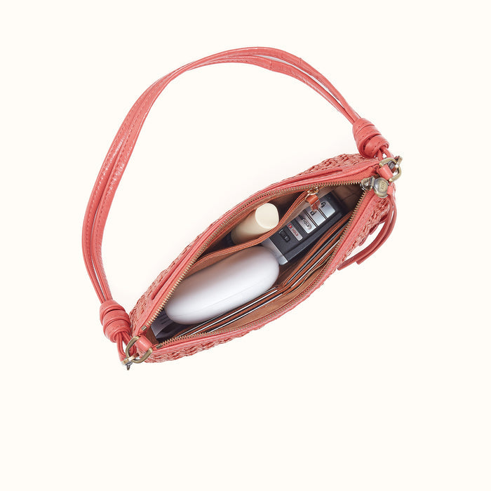 Pink handbag with cosmetic items on a light gray background