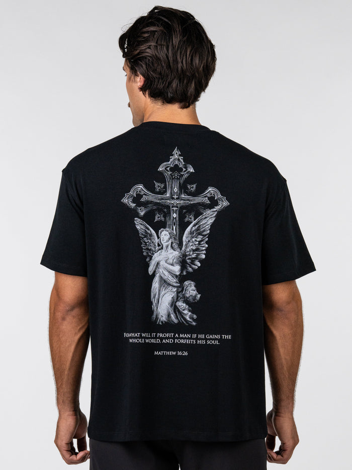 Person wearing a black t-shirt with an angel and cross design on the back, against a white background.
