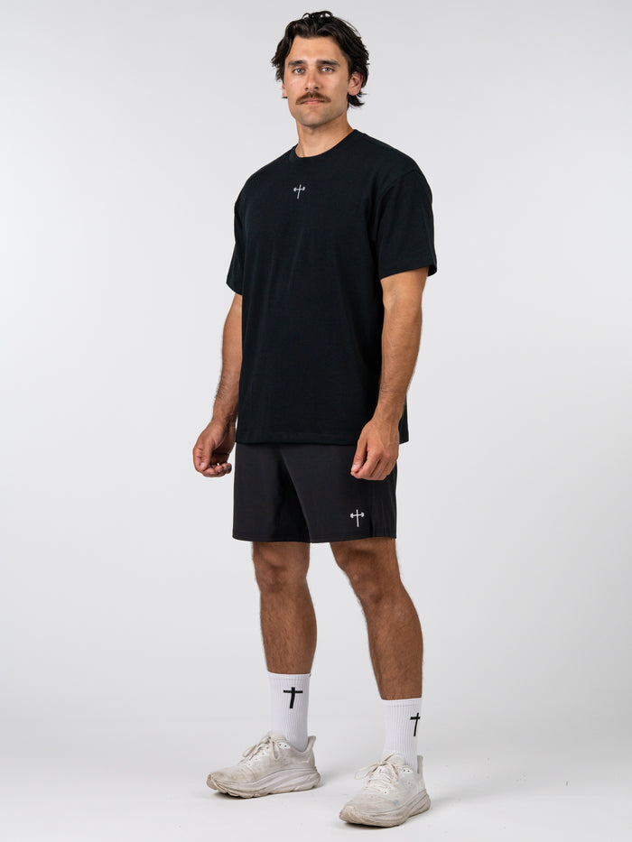 Man wearing a black t-shirt and shorts with a white background