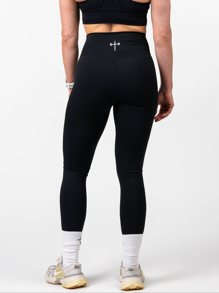 Person wearing black sports bra and leggings on a white background