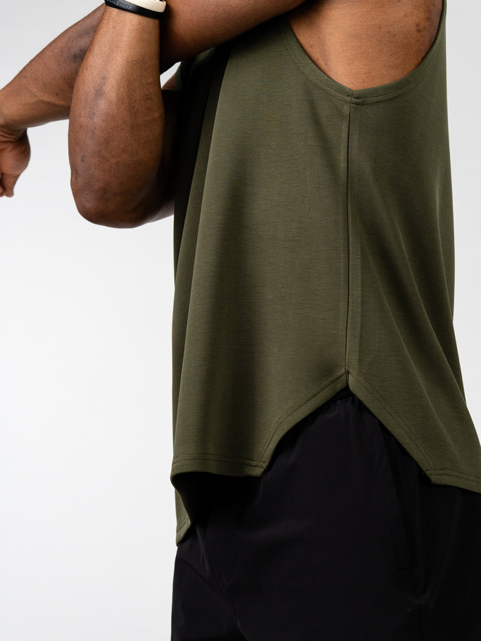Close-up of a person stretching their arm while wearing an olive green Essential Sleeveless Hoodie, showcasing lightweight, breathable fabric designed for unrestricted movement during workouts.
