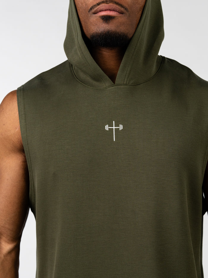 Close-up of a man wearing an olive green Essential Sleeveless Hoodie featuring a small white barbell cross logo on the chest, designed for freedom of movement in Christian fitness apparel.