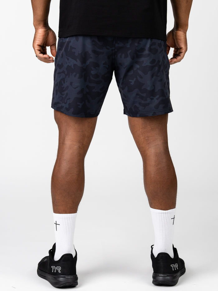 Rear view of a person wearing navy camo Essential Training Shorts, white socks with black cross symbols, and black athletic shoes, showcasing lightweight, breathable Christian workout apparel.