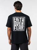 Man wearing black Faith Over Fear Premium Oversized Tee with bold white graphic text on back in a relaxed fit, styled for Christian fitness apparel and activewear.