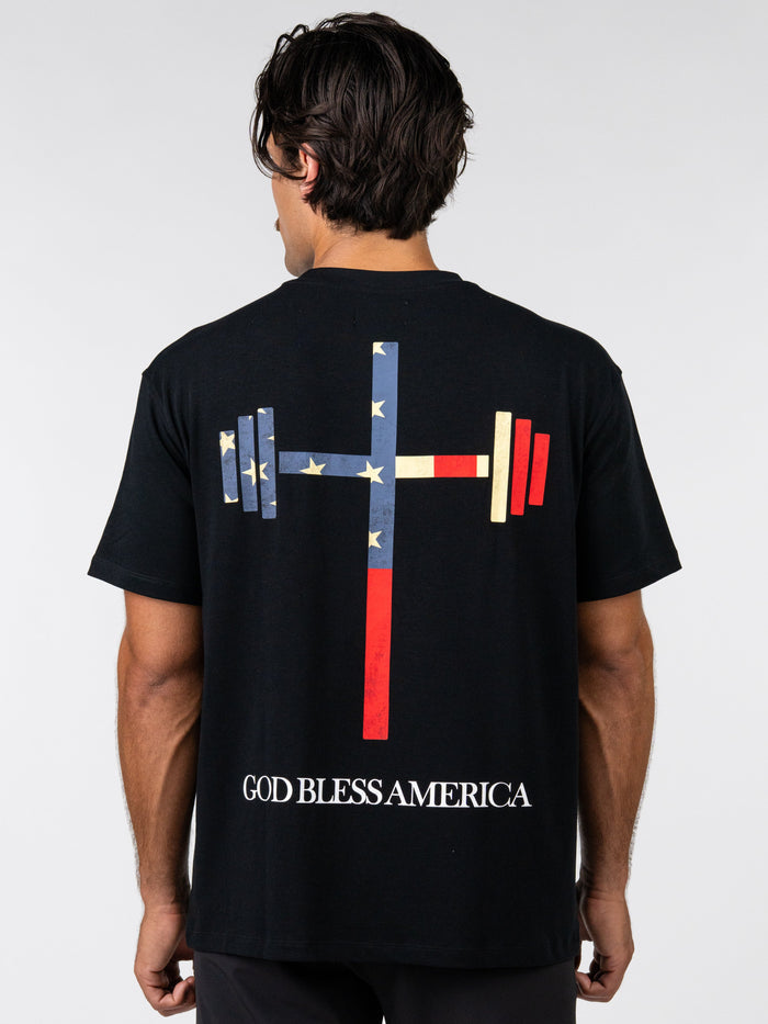 Person wearing a black t-shirt with a graphic design on the back and 'God Bless America' text.