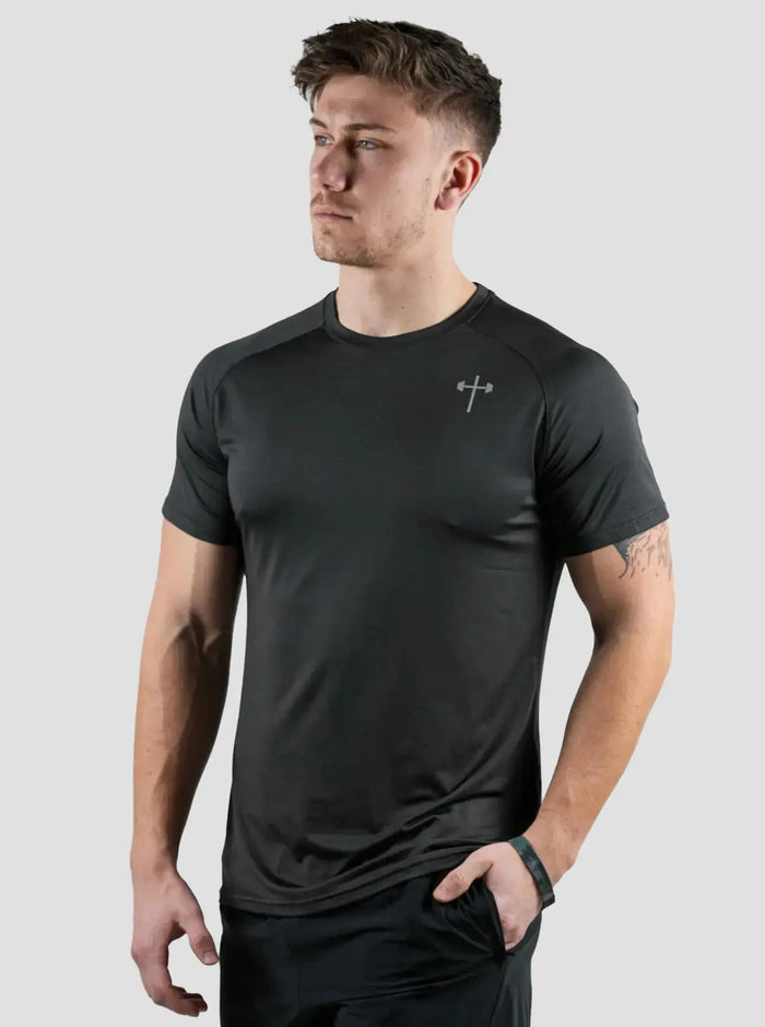 Man wearing a black athletic shirt with a brand logo on a light gray background