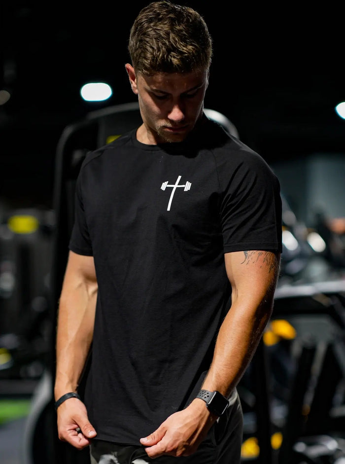 Man wearing a black t-shirt with a white logo, gym view