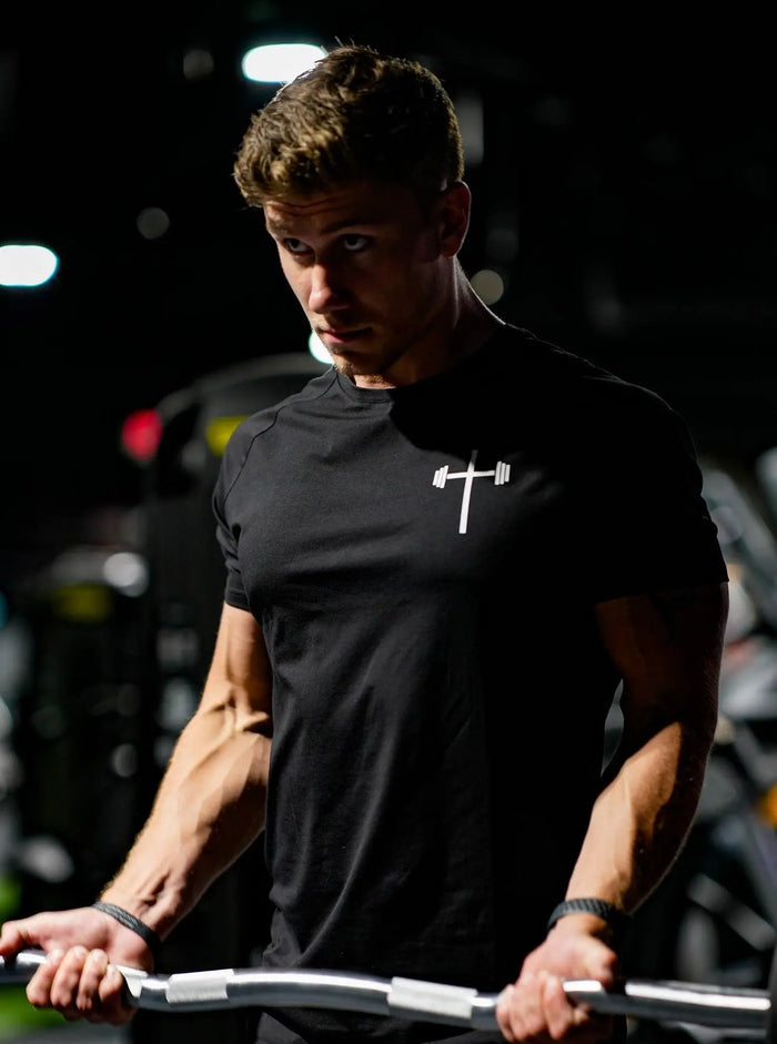 Man wearing a black t-shirt with a white logo, lifting view