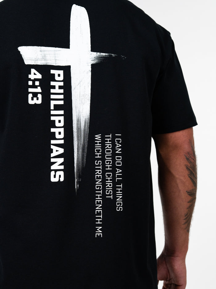 Phil 4:13 Premium Oversized Tee featuring a black background with a large white cross graphic and bold text of Philippians 4:13, highlighting Christian gym clothing and faith-based fitness apparel.