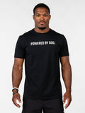A man wearing a black short-sleeve t-shirt with the white printed text 'POWERED BY GOD.' across the chest, standing against a light gray studio background.