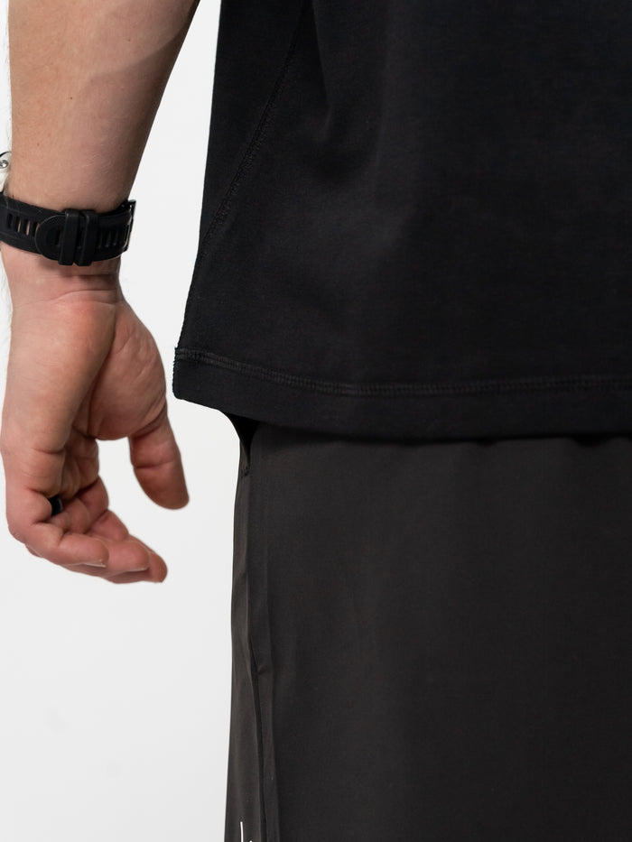 Person wearing a black t-shirt and black shorts on a white background