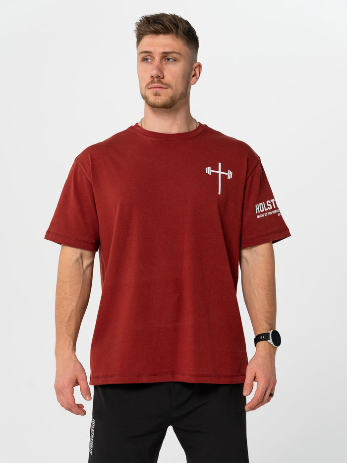 Man wearing a maroon t-shirt with a logo and text on a white background