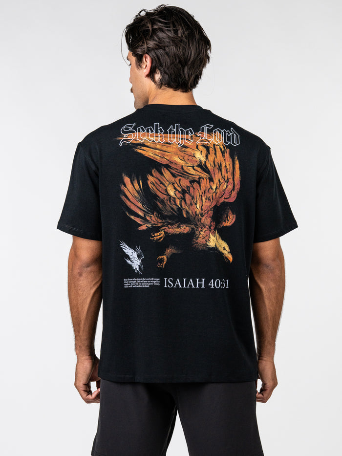 Back view of a man wearing a black Seek the Lord Premium Oversized Tee featuring a large graphic of an eagle in flight, text "Seek the Lord", and Isaiah 40:31 scripture reference.