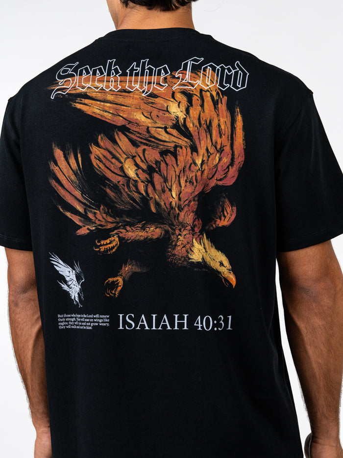 Back view of a person wearing a black Seek the Lord Premium Oversized Tee featuring a large detailed eagle graphic, the text "Seek the Lord," and the Bible verse Isaiah 40:31.