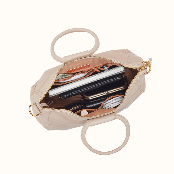 Beige handbag with circular handles, open to reveal its contents on a white background