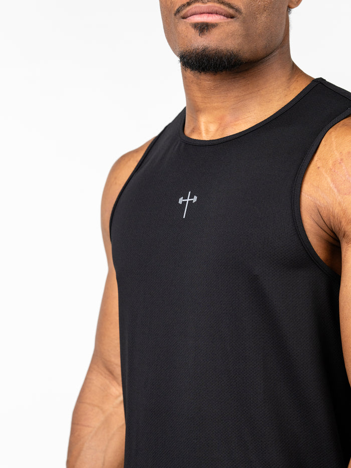 Close-up of a man wearing a black Signature Tank with a subtle silver Christian cross and barbell design on the chest, made from breathable, performance fabric.