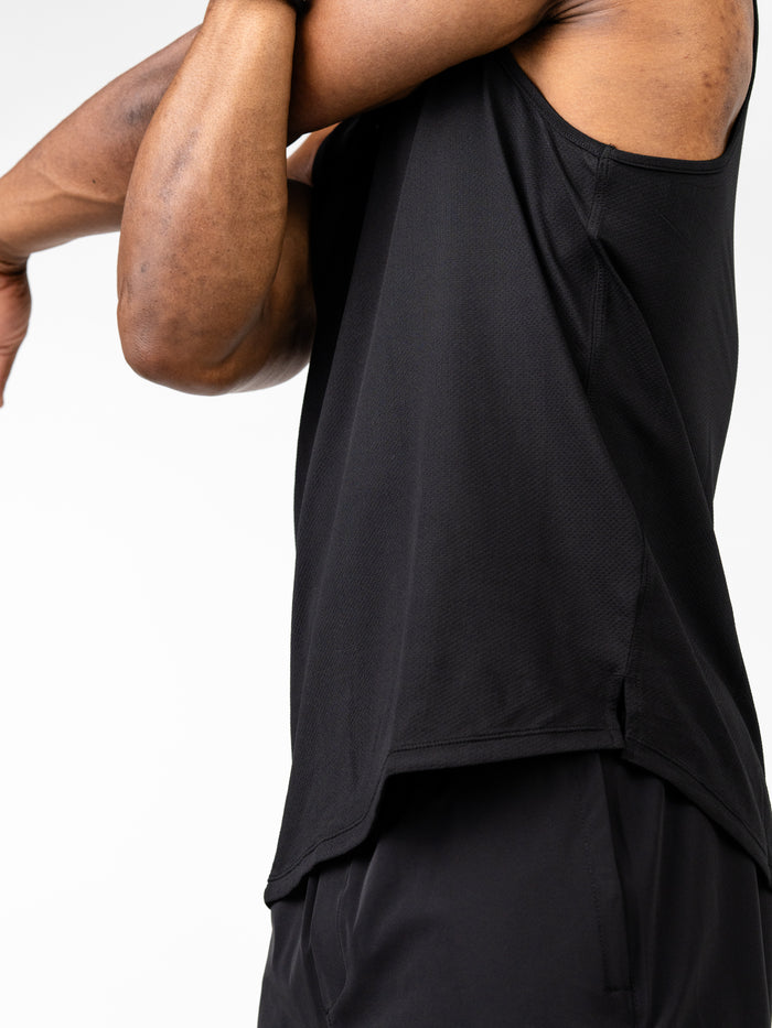 Close-up of a person wearing a black Signature Tank sleeveless performance tee designed for intense training, showing breathable, sweat-wicking fabric and 4-way stretch fit.