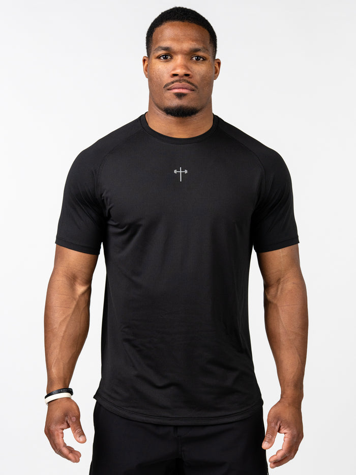 Male model wearing a black Signature Tee featuring a subtle cross with a barbell design on the chest, designed for performance with breathable, stretch fabric suitable for Christian fitness apparel.