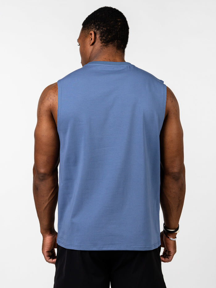 Man wearing a blue Vital Cross Sleeveless Tank viewed from the back, paired with black shorts, showcasing the tank's clean, durable fabric designed for high-output training.