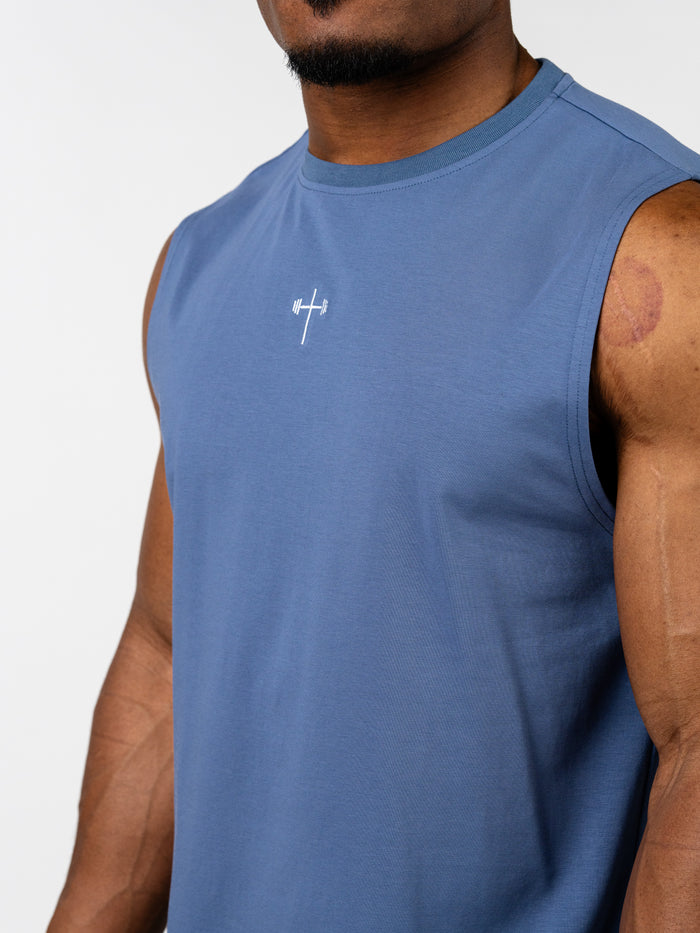 Close-up of a man wearing a blue Vital Cross Sleeveless Tank featuring a small white cross with a barbell design at the center chest, designed for Christian gym clothing and activewear.