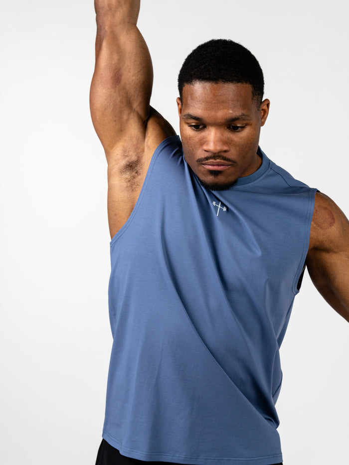 Athletic man wearing a blue Vital Cross Sleeveless Tank with a Christian cross and barbell design, demonstrating high-output training comfort and unrestricted movement.