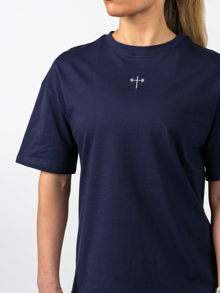 Woman wearing a navy Women's Lifting Club Oversized Tee with a small white cross and barbell design on the chest, representing Christian fitness apparel and strength.