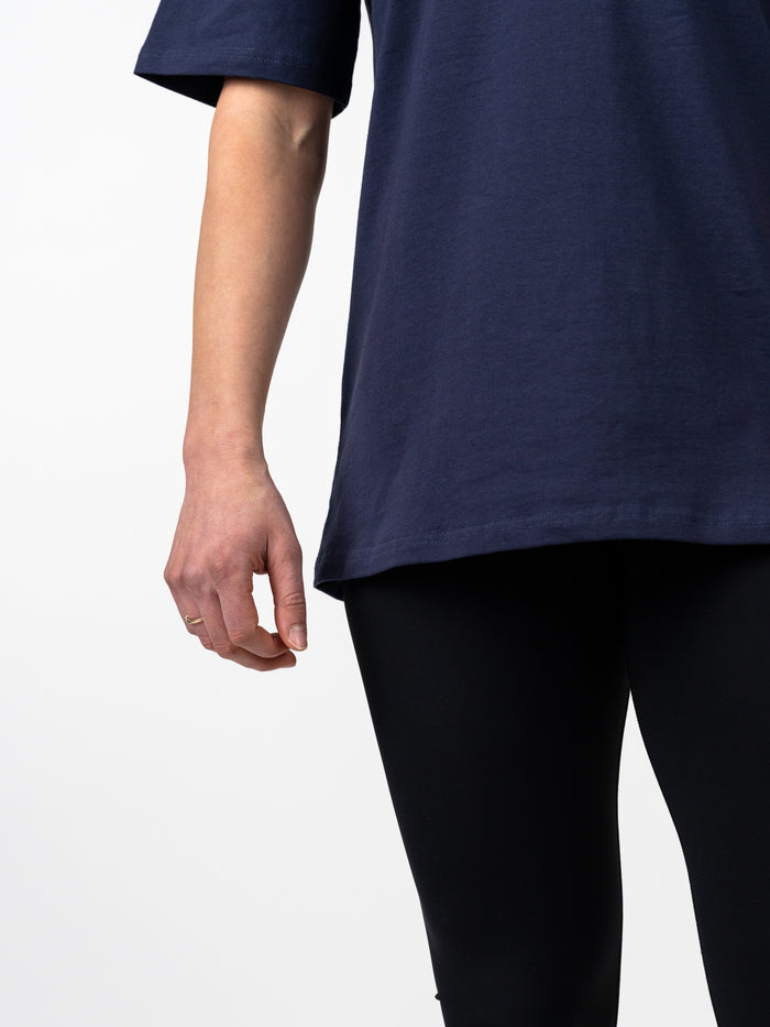 Close-up of a woman wearing a navy Women's Lifting Club Oversized Tee paired with black leggings, showcasing the relaxed fit and casual style of this Christian fitness apparel.
